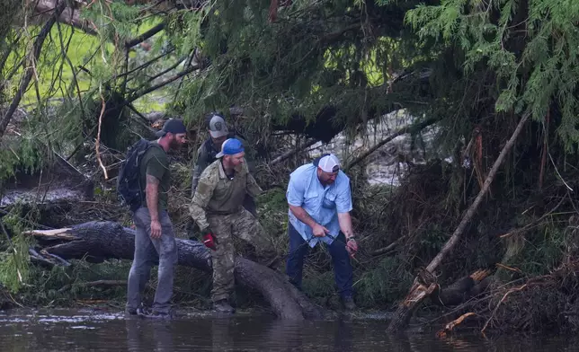 People remove debris from the Guadalupe River while inspecting an area at Camp Mystic, Sunday, July 6, 2025, in Hunt, Texas, after a flash flood swept through the area. (AP Photo/Julio Cortez)