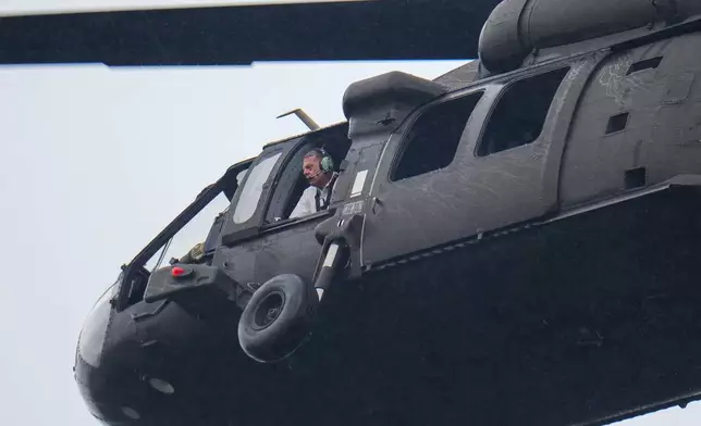 An official looks out a helicopter while flying over Camp Mystic along the banks of the Guadalupe River, Sunday, July 6, 2025, in Hunt, Texas, after a flash flood swept through the area. (AP Photo/Julio Cortez)