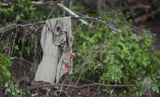 Patches cover a shirt hanging on a tree, across the Guadalupe River from Camp Mystic, Saturday, July 5, 2025, in Hunt, Texas, after a flash flood swept through the area. (AP Photo/Julio Cortez)