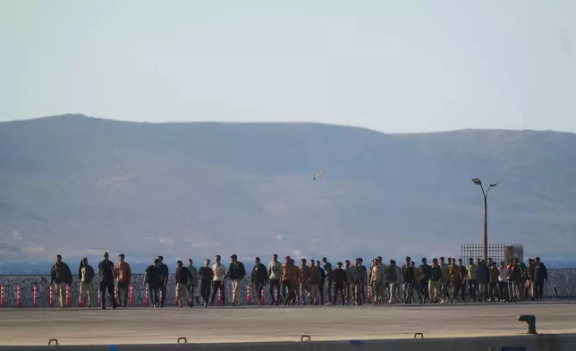 Migrants rescued south of Crete walk after their arrival at the the port of Lavrio, Greece, on Thursday, July 10, 2025. (AP Photo/Petros Giannakouris)