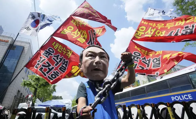 A protester wears a mask of former South Korean President Yoon Suk Yeol during a rally in support of a hearing to review a special prosecutor's request for his arrest, near the Seoul Central District Court in Seoul, South Korea, on Wednesday, July 9, 2025. The writing reads "Yoon Suk Yeol sentenced to death." (AP Photo/Ahn Young-joon)