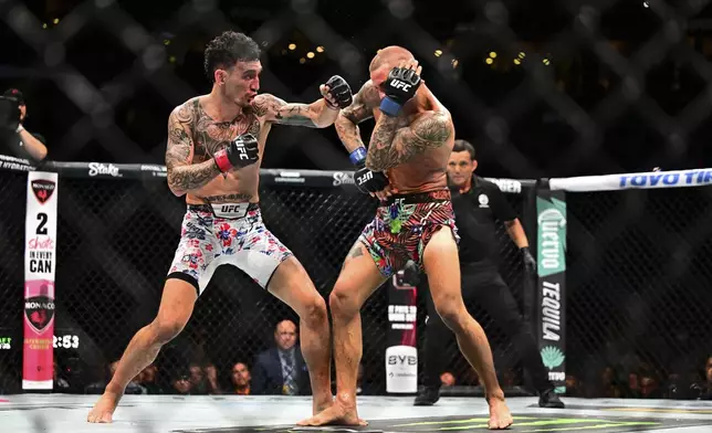 Max Holloway, left, hits Dustin Poirier in a lightweight title fight at UFC 318 in New Orleans, La., Saturday, July 19, 2025. (AP Photo/Ella Hall)