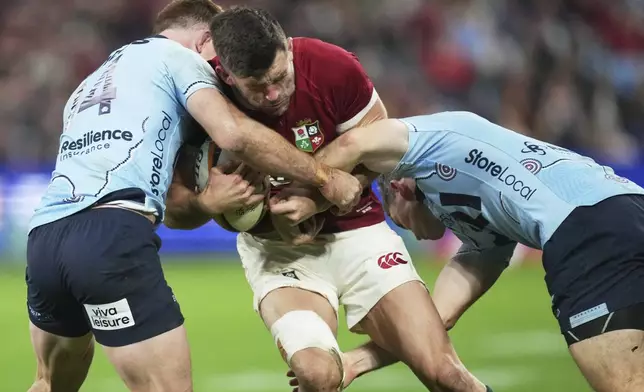 Blair Kinghorn of the British &amp; Irish Lions is tackled by defenders during the Lions and Waratahs rugby match in Sydney, Australia, Saturday, July 5, 2025. (AP Photo/Mark Baker)