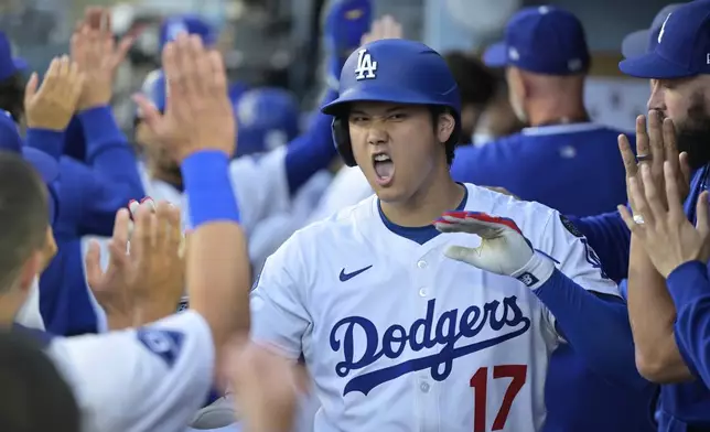 Los Angeles Dodgers' Shohei Ohtani (17) is congratulated by teammates after hitting a two-run home run against the Minnesota Twins during the first inning of a baseball game in Los Angeles, Monday, July 21, 2025. (AP Photo/Jayne Kamin-Oncea)
