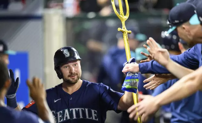 Seattle Mariners' Cal Raleigh is greeted by teammates after hitting a home run during the sixth inning of a baseball game against the Los Angeles Angels, Saturday, July 26, 2025, in Anaheim, Calif. (AP Photo/William Liang)