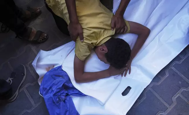 A Palestinian boy mourns over the body of his 12-year-old friend, Abdullah Ahmed, who was killed in an Israeli strike that targeted a drinking water distribution point, at Al-Awda Hospital in Nuseirat, central Gaza Strip, Sunday, July 13, 2025. (AP Photo/Abdel Kareem Hana)