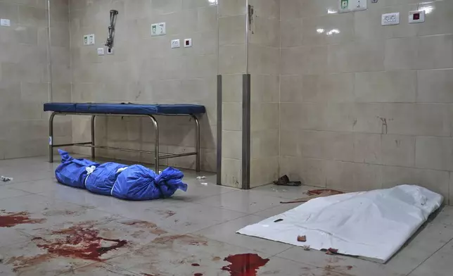 Bodies of Palestinians killed in Israeli strikes, wrapped in plastic bags, lie on the ground at Al-Awda Hospital in Nuseirat, central Gaza Strip, Sunday, July 13, 2025. (AP Photo/Abdel Kareem Hana)