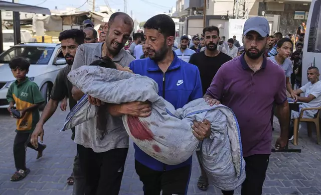 Relatives carry the body of 13-year-old Seraje Ebrahim, killed in an Israeli strike on a drinking water distribution point, for burial outside Al-Awda Hospital in Nuseirat, central Gaza Strip, Sunday, July 13, 2025. (AP Photo/Abdel Kareem Hana)