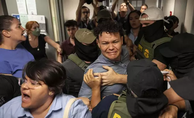 Federal agents detain Carlos Javier Lopez Benitez, center, from Paraguay as they pull away his sister, Porfiria Lopez, a U.S. citizen, left, outside immigration court at the Jacob K. Javits federal building, Wednesday, July 16, 2025, in New York. (AP Photo/Yuki Iwamura)