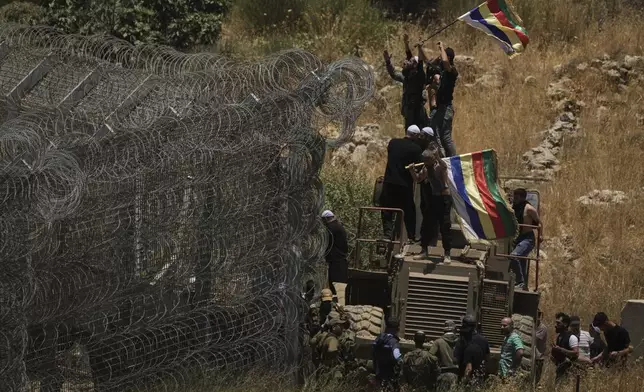 Syrian Druze protest near the Israeli-Syrian border, as seen from the town of Majdal Shams in the Israeli-controlled Golan Heights, Wednesday, July 16, 2025, amid the ongoing clashes between Syrian government forces and Druze armed groups in the southern Syrian city of Sweida. (AP Photo/Leo Correa)