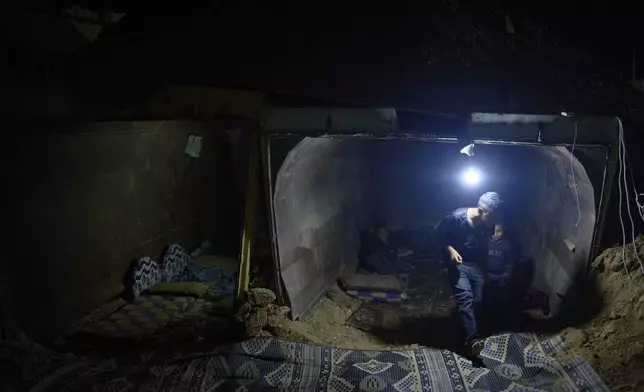 The Gaboa family, Bedouins living in Al-Furaa village in southern Israel, gather around the makeshift bomb shelter they made from two gravel trucks buried in dirt to protect them from incoming Iranian fire, Tuesday, June 17, 2025. (AP Photo/Maya Alleruzzo)