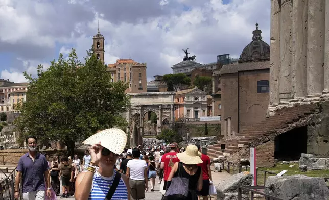 Tourists use use fans and sun hats as they visit the Forum in Rome on Tuesday, July 22, 2025. (AP Photo/Gregorio Borgia)