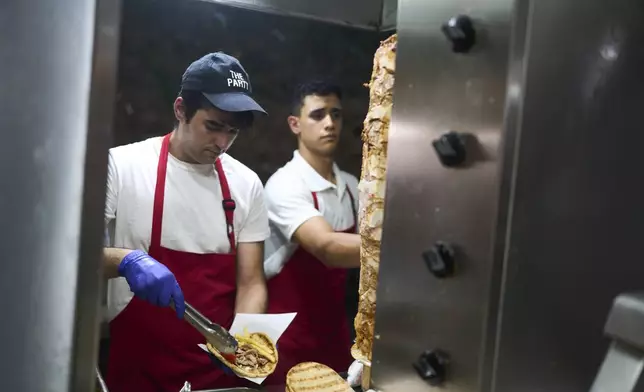 Grill cook Thomas Siamandas makes traditional souvlaki in a restaurant in the central Monastiraki district during a hot day in Athens on Wednesday, July 16, 2025. (AP Photo/Petros Giannakouris)