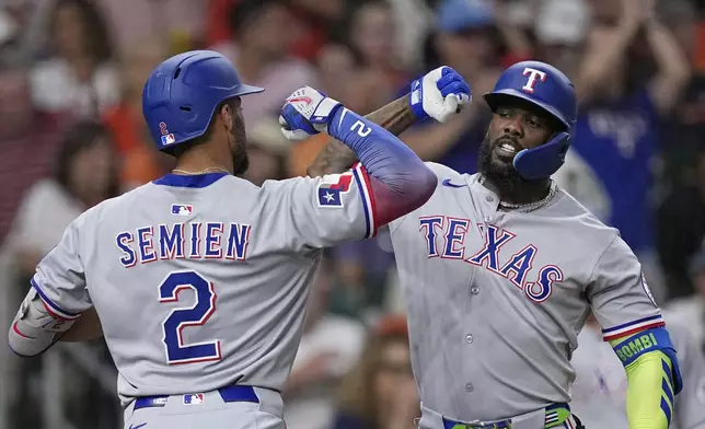 Texas Rangers' Marcus Semien (2) celebrates with Adolis García after hitting a home run against the Houston Astros during the eighth inning of a baseball game Saturday, July 12, 2025, in Houston. (AP Photo/David J. Phillip)