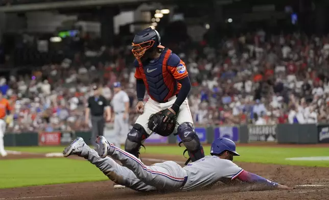 Texas Rangers' Marcus Semien (2) scores as Houston Astros catcher Yainer Diaz waits for the throw during the 11th inning of a baseball game Saturday, July 12, 2025, in Houston. (AP Photo/David J. Phillip)