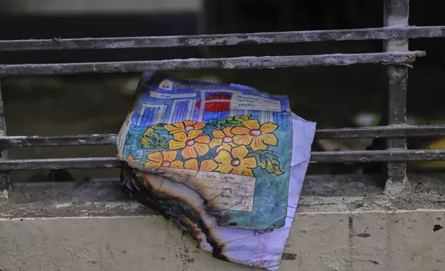 A burnt book of a student is seen at the window of a school after a Bangladesh air force training jet crashed into it Monday in Dhaka, Bangladesh, Tuesday, July 22, 2025. (AP Photo/Mahmud Hossain Opu)