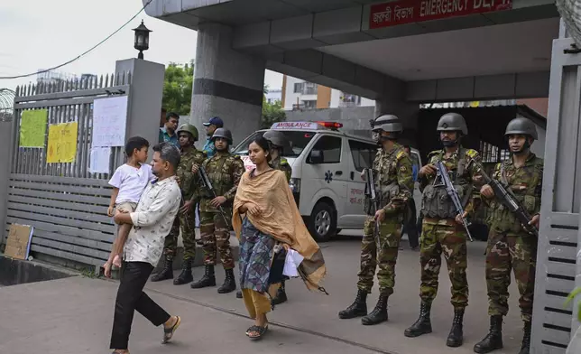 Law enforcement officers stand guard at the entrance of the National Institute of Burn and Plastic Surgery as survivors are treated inside after a Bangladesh air force training aircraft crashed into a school in the nation's capital Monday afternoon in Dhaka, Bangladesh, Tuesday, July 22, 2025.( AP Photo/ Mahmud Hossain Opu)