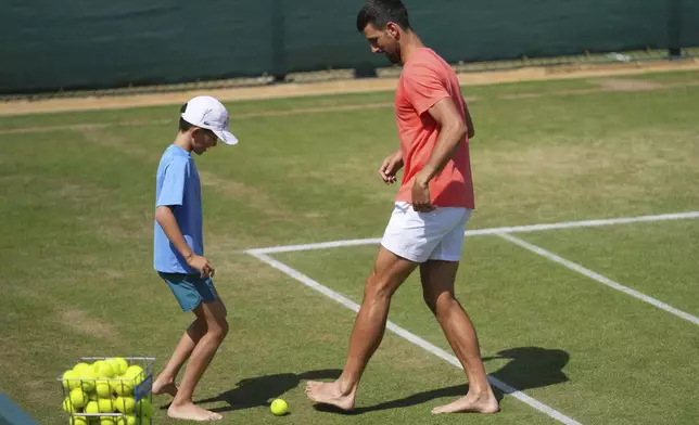 Serbia's Novak Djokovic plays soccer barefoot with his son Stefan on the practice courts on day nine at the Wimbledon Tennis Championships in London, Tuesday, July 8, 2025. (AP Photo/Joanna Chan)