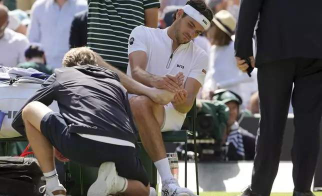 Taylor Fritz of the U.S. gets medical assistance during the men's singles quarter final match against Karen Khachanov of Russia at the Wimbledon Tennis Championships in London, Tuesday, July 8, 2025.(AP Photo/Kin Cheung)