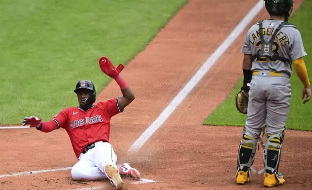 Cleveland Guardians' Angel Martínez slides safely into home plate to score a run on an RBI-single by David Fryduring the first inning of a baseball game against the Athletics, Sunday, July 20, 2025, in Cleveland. (AP Photo/David Dermer)