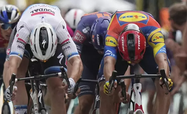 Belgium's Tim Merlier, left, and Italy's Jonathan Milan cross the finish line during the third stage of the Tour de France cycling race over 178.3 kilometers (110.8 miles) with start in Valenciennes and finish in Dunkerque, France, Monday, July 7, 2025. (AP Photo/Thibault Camus)