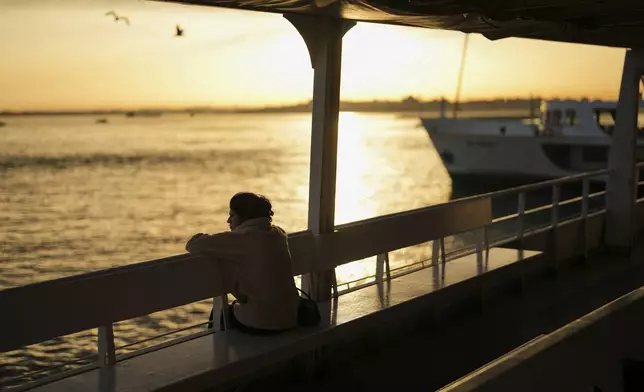 A woman peers out from a ferry departing Kadikoy on the Asian side of Istanbul, Turkey, Friday, May 23, 2025. (AP Photo/Francisco Seco)