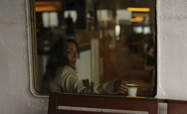 A woman drinks tea on a ferry crossing the Bosphorus in Istanbul, Turkey, Sunday, May 25, 2025. (AP Photo/Francisco Seco)