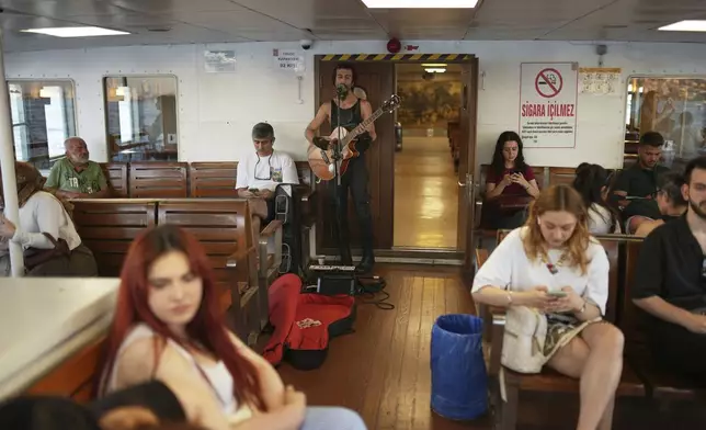 A musician performs for money on a ferry crossing the Bosphorus in Istanbul, Turkey, Tuesday, June 24, 2025. (AP Photo/Francisco Seco)