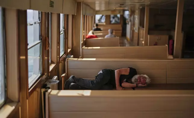 A man sleeps on a ferry crossing the Bosphorus in Istanbul, Turkey, Friday, May 23, 2025. (AP Photo/Francisco Seco)