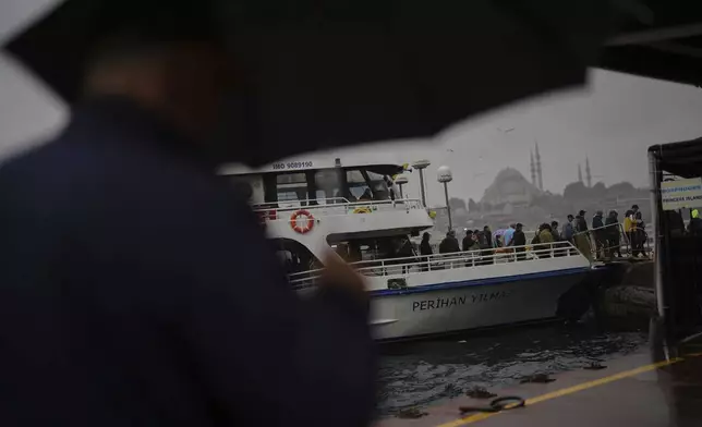 Commuters disembark from a ferry at the Eminonu terminal on a rainy day in Istanbul, Turkey, Monday, May 26, 2025. (AP Photo/Francisco Seco)