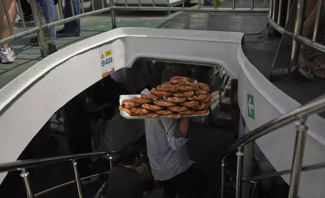 A man sells the popular Turkish bread "simit" on a ferry bound for the Princes' Islands in the Sea of Marmara, in Istanbul, Turkey, Saturday, May 24, 2025. (AP Photo/Francisco Seco)