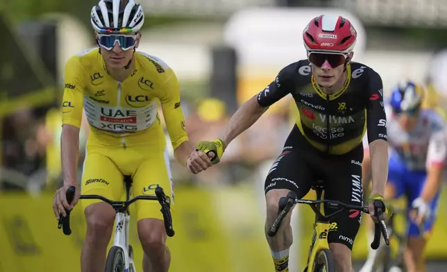 Slovenia's Tadej Pogacar, wearing the overall leader's yellow jersey, and Denmark's Jonas Vingegaard, cross the finish line hand-in-hand of the the tenth stage of the Tour de France cycling race over 165.3 kilometers (102.7 miles) with start in Ennezat and finish in Le Mont-Dore Puy de Sancy, France, Monday, July 14, 2025. (AP Photo/Mosa'ab Elshamy)