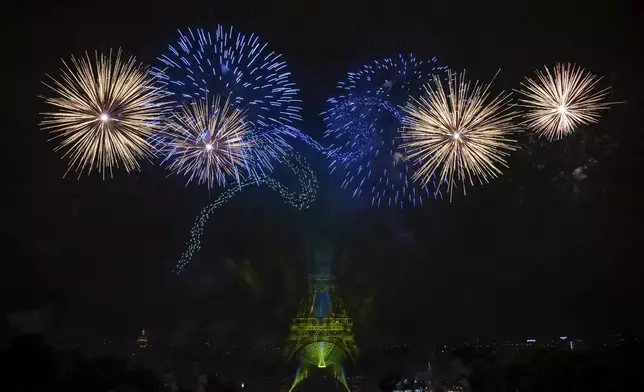 Fireworks and drones illuminate the Eiffel Tower in Paris, during Bastille Day celebrations late Monday, July 14, 2025. (AP Photo/Aurelien Morissard)
