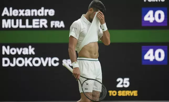 Novak Djokovic of Serbia wipes his face as he plays Alexandre Muller of France during their first round men's singles match at the Wimbledon Tennis Championships in London, Tuesday, July 1, 2025. (AP Photo/Kin Cheung)