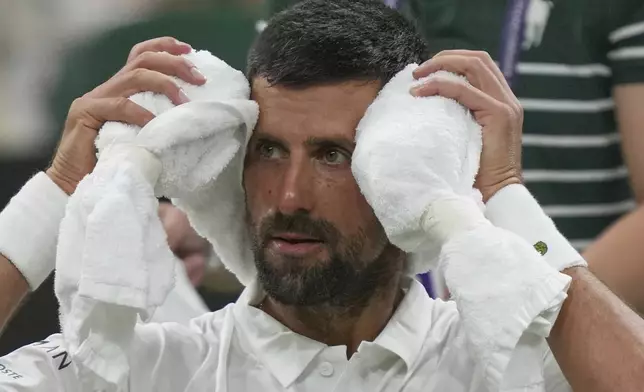 Novak Djokovic of Serbia places a cold towel around his head during a change of ends break against Alexandre Muller of France during their first round men's singles match at the Wimbledon Tennis Championships in London, Tuesday, July 1, 2025. (AP Photo/Kin Cheung)