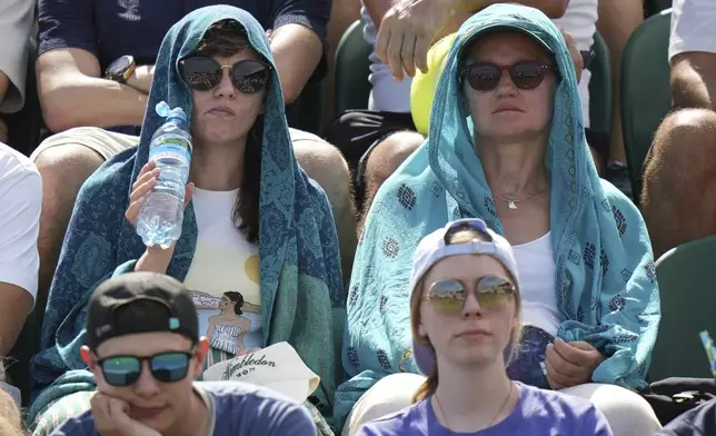 Spectators sit in the sun on day two at the Wimbledon Tennis Championships in London, Tuesday, July 1, 2025. (AP Photo/Alastair Grant)