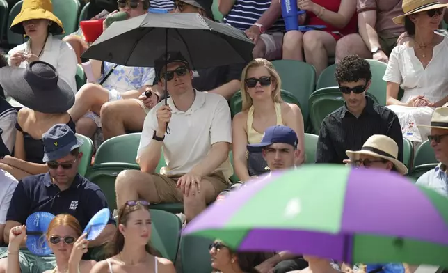 Spectators try to keep cool on day two at the Wimbledon Tennis Championships in London, Tuesday, July 1, 2025. (AP Photo/Alastair Grant)