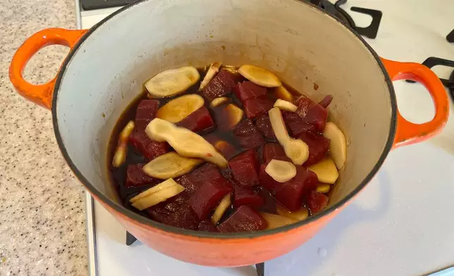 Chopped tuna and sliced ginger simmer in a sauce consisting of soy sauce, mirin, sake, sugar and salt to make tsukudani, a Japanese preserved food on Monday, June 30, 2025. (AP Photo/Yuri Kageyama)