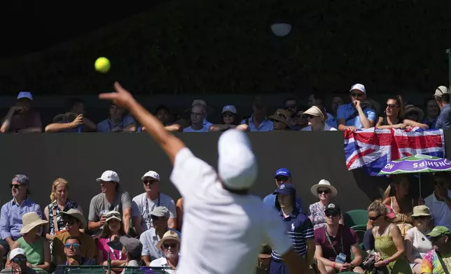 Spectators watch as Leandro Riedi of Switzerland serves to Oliver Tarvet of Britain during their first round singles match at the Wimbledon Tennis Championships in London, Monday, June 30, 2025. (AP Photo/Joanna Chan)