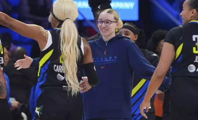 An injured Dallas Wings guard Paige Bueckers, center, reaches to teammates from the bench during a timeout during the first half of a WNBA basketball game against the Las Vegas Aces in Arlington, Texas, Sunday, July 27, 2025. (AP Photo/LM Otero)