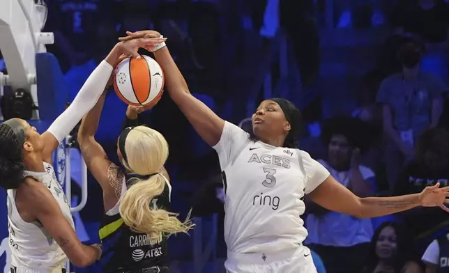 Dallas Wings guard DiJonai Carrington is stopped by Las Vegas Aces forward NaLyssa Smith (3) and center A'ja Wilson (22) during the second half of a WNBA basketball game in Arlington, Texas, Sunday, July 27, 2025. (AP Photo/LM Otero)
