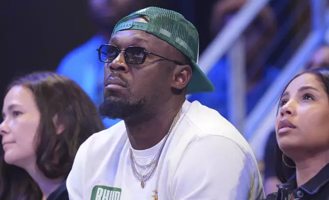 Olympic champion sprinter Usain Bolt, center, watches the second half of a WNBA basketball game between the Las Vegas Aces and the Dallas Wings in Arlington, Texas, Sunday, July 27, 2025. (AP Photo/LM Otero)