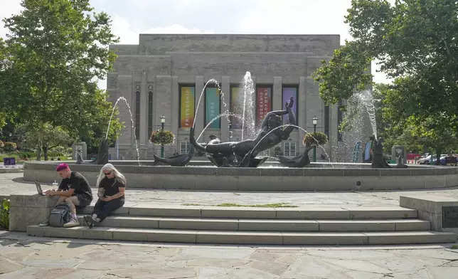 Guests sit by a fountain on the campus of Indiana University, Thursday, July 17, 2025, in Bloomington, Ind. (AP Photo/Darron Cummings)