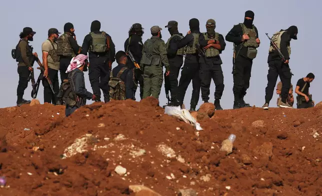FILE - Syrian government security forces gather on a hillside as a convoy of ambulances and buses arrives at a checkpoint in the village of Busra al-Harir, southern Syria, on its way to Sweida province, Tuesday, July 22, 2025. (AP Photo/Omar Sanadiki, File)