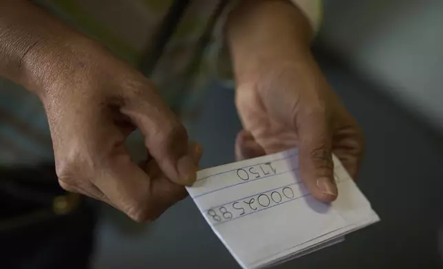Som Xin, originally from Laos, holds a part number number provided by phone by her detained boyfriend, as she inquires about his whereabouts outside the ICE Los Angeles Staging Facility looking to find him in Los Angeles on Wednesday, June 25, 2025. (AP Photo/Damian Dovarganes)