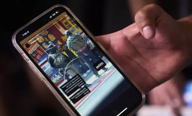 A teenage boy shows a social media post showing the arrest of his father by federal agents, as he stands outside the ICE Los Angeles Staging Facility looking for the location of his father in Los Angeles on Wednesday, June 25, 2025. (AP Photo/Damian Dovarganes)