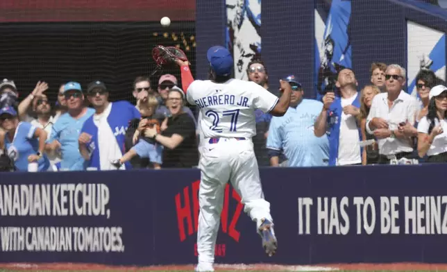 Toronto Blue Jays first base Vladimir Guerrero Jr. (27) makes a running catch during fourth inning MLB baseball action against the San Francisco Giants in Toronto on Saturday, July 19, 2025. (Nathan Denette/The Canadian Press via AP)