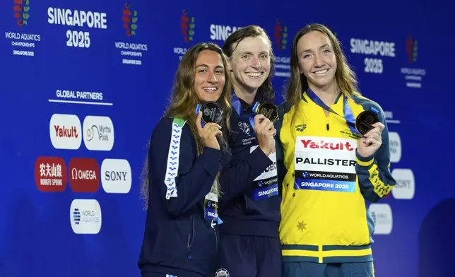 Gold medalist Katie Ledecky of the United States, center, flanked by silver medalist Simona Quadarella of Italy, left, and bronze medalist Lani Pallister of Australia pose on the podium after the women's 1500m freestyle final at the World Aquatics Championships in Singapore, Tuesday, July 29, 2025. (AP Photo/Vincent Thian)