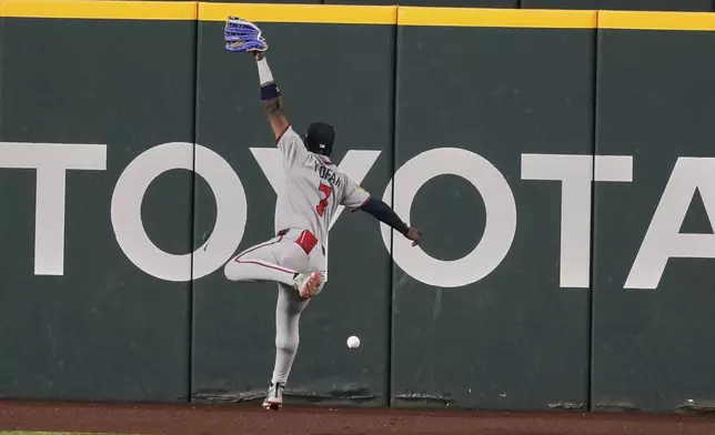 Atlanta Braves left fielder Jurickson Profar makes a leaping attempt to catch a run-scoring double by Texas Rangers' Sam Haggerty in the fifth inning of a baseball game Friday, July 25, 2025, in Arlington, Texas. (AP Photo/Tony Gutierrez)