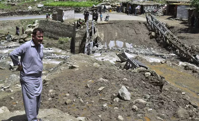 Local residents examine a damage bridge following a cloudburst triggered landslide and flash flood on a highway near the Chilas district, northern Pakistan, Wednesday, July 23, 2025. (AP Photo/Saqib Manzoor)